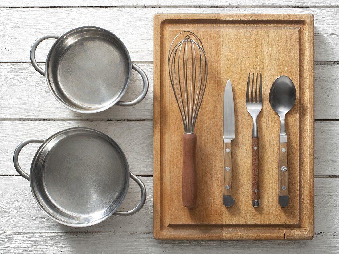 Assorted kitchen utensils: saucepans, cutlery and a whisk