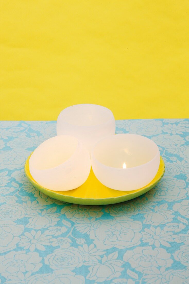 DIY bowl-shaped candles on yellow plate against yellow background