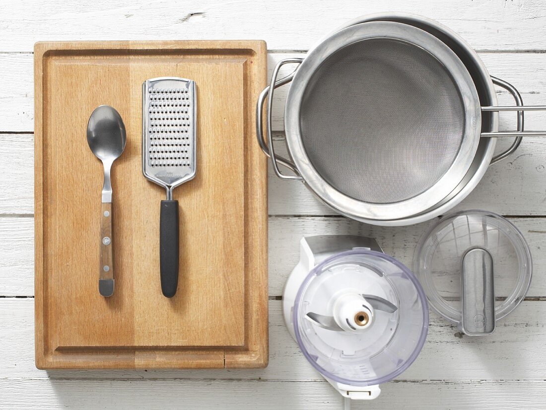 Assorted kitchen utensils: a grater, a sieve, a saucepan and a chopper