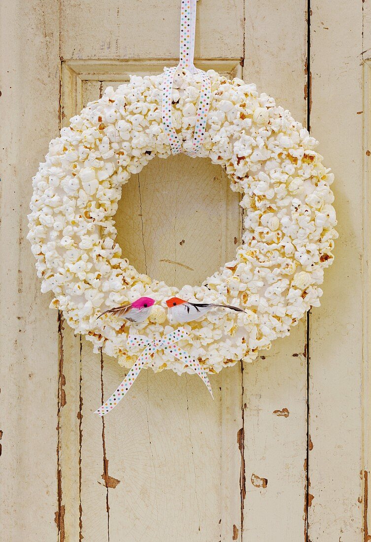 Hand-made popcorn wreath with bird ornaments and ribbon hung on door