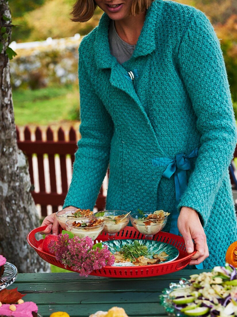 Frau serviert Pilzsuppe fürs Herbstbuffet im Freien