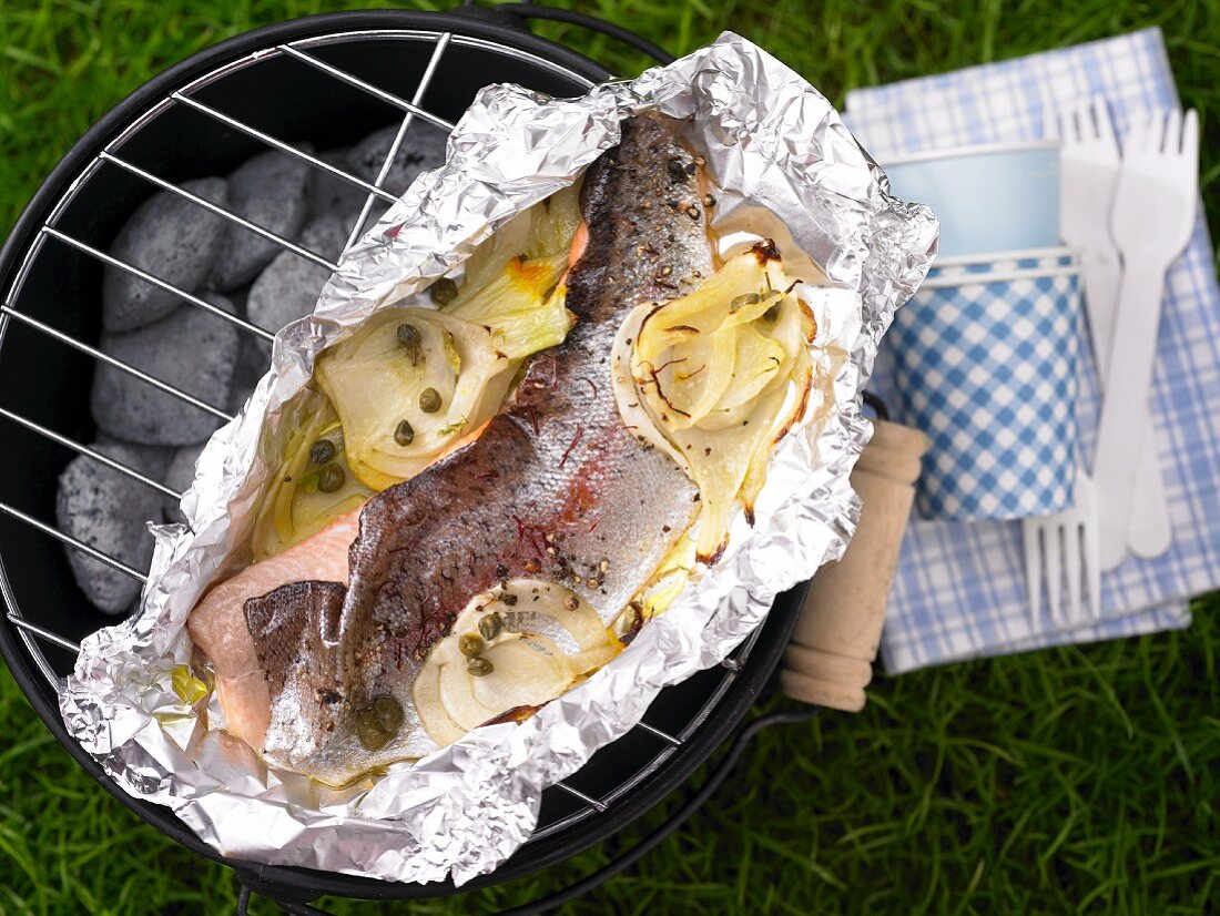 A trout fillet parcel on a charcoal barbecue