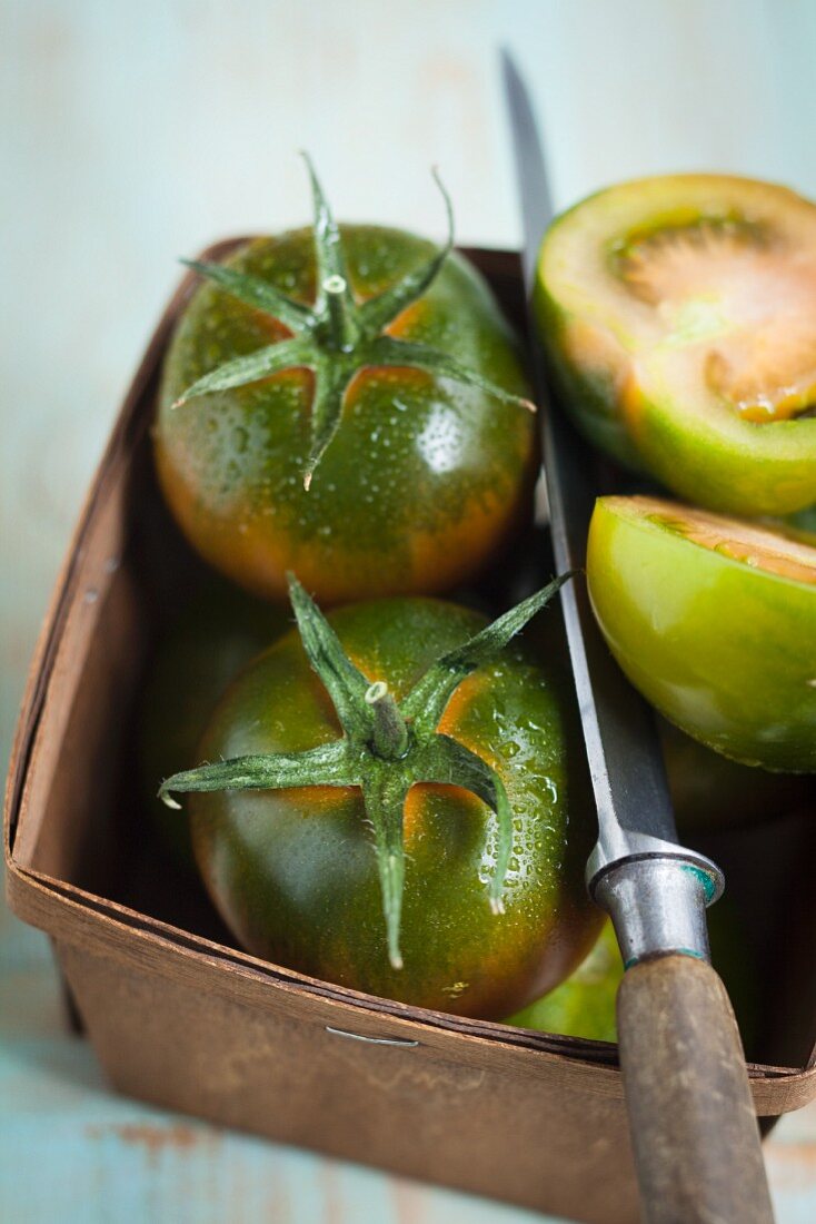 Grüne Tomaten mit Messer im Spankorb