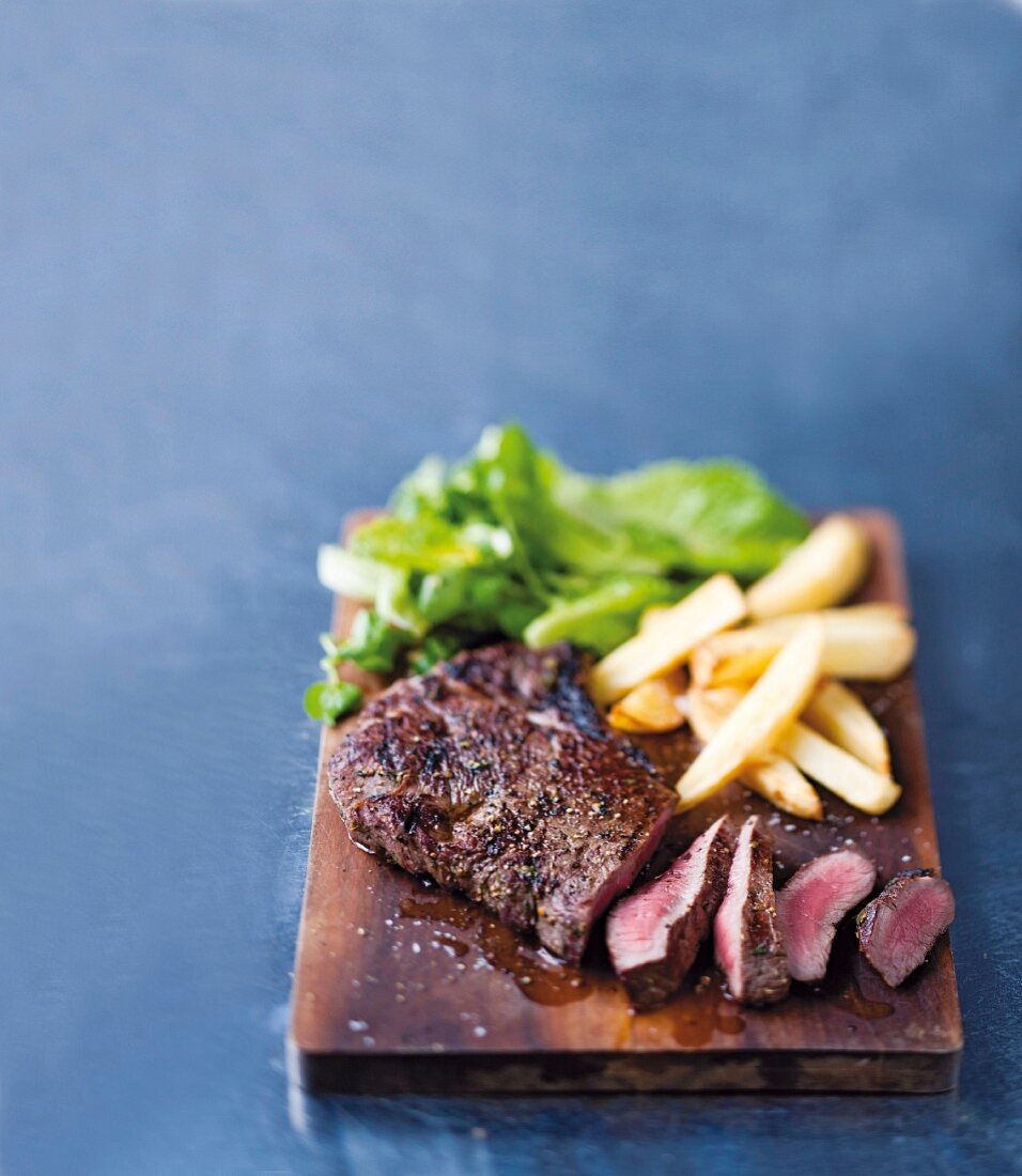 Grilled beef steak with chips on a wooden board
