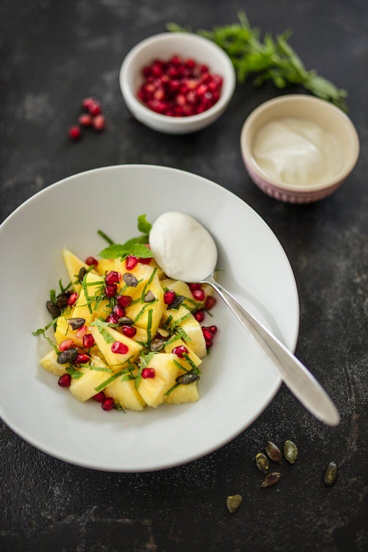 Pineapple salad with pomegranate seeds and soya yoghurt (vegan)