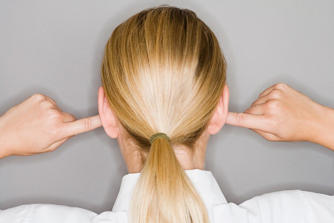 A blonde woman with her fingers in her ears