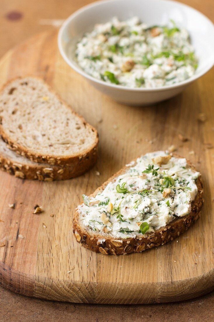 Brotscheibe mit Ziegenkäse, Frühlingszwiebeln, Löwenzahn, Thymian und Walnüssen