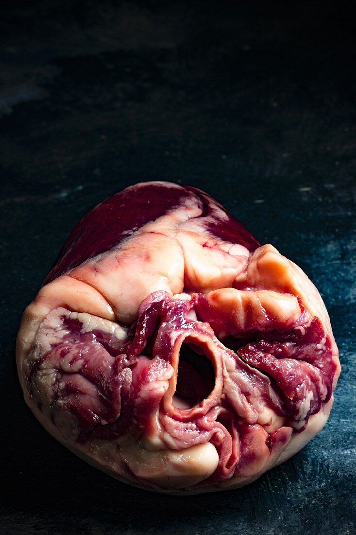A close-up of a raw lamb heart against a dark background