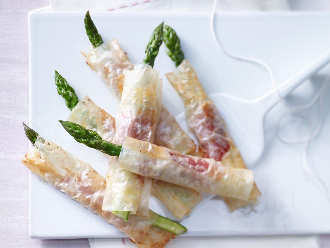 Green aspargus wrapped in crispy pastry with ham and cheese