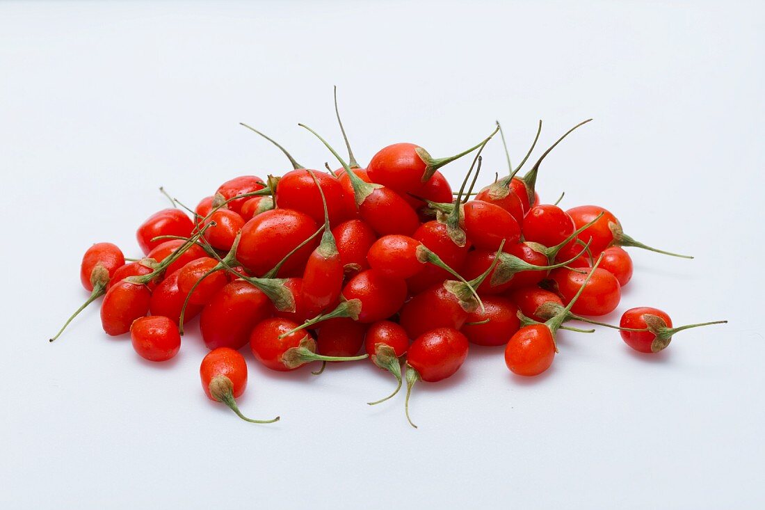 A pile of fresh goji berries on a white surface