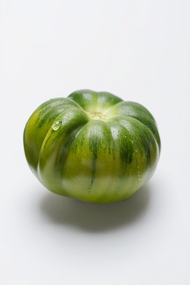 Eine grüne Tomate vor weißem Hintergrund