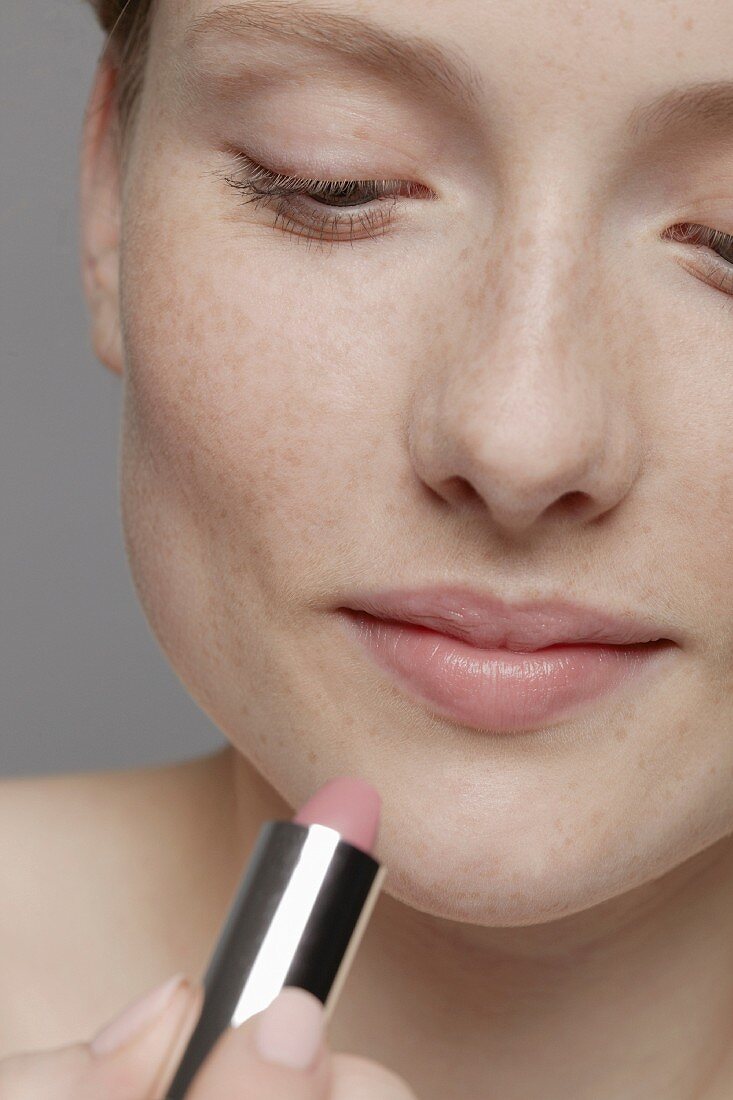 A woman applying lipstick