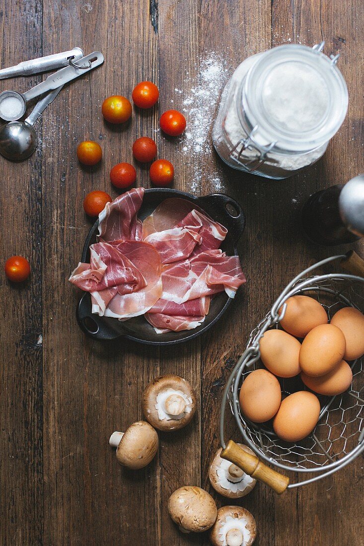 Zutatenstilleben für Tomatenquiche mit Schinken und Pilzen