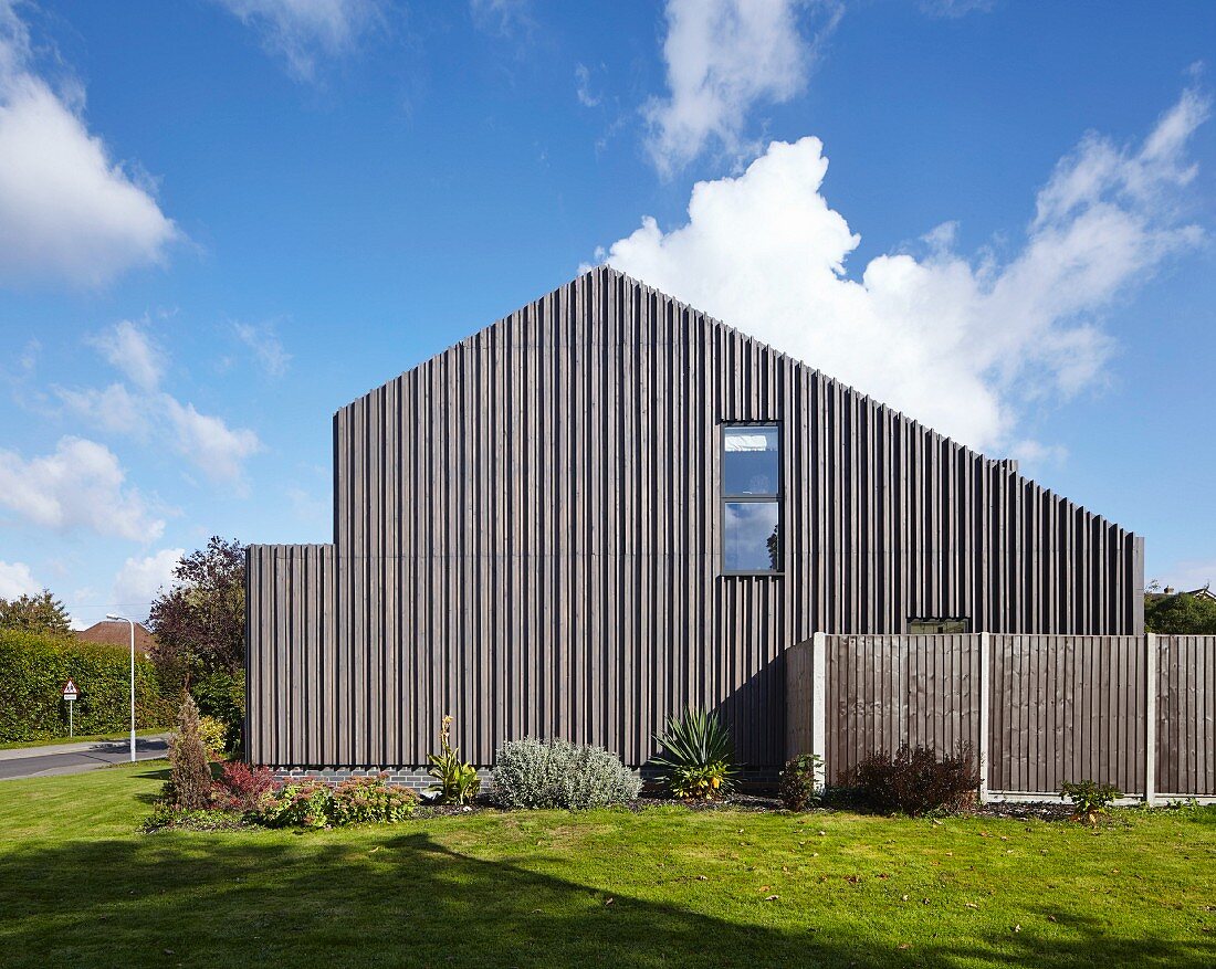 Moderne, holzverkleidete Giebelfassade unter blauem Himmel