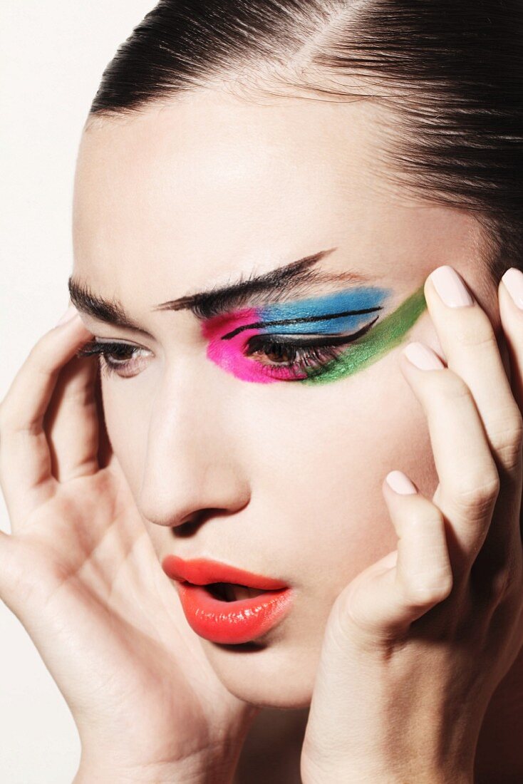 A brunette woman with extravagant and colourful make-up
