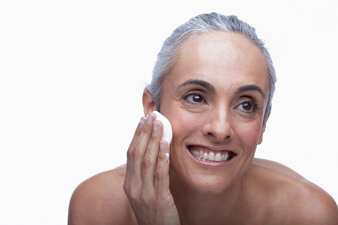 An older woman using facial cleanser