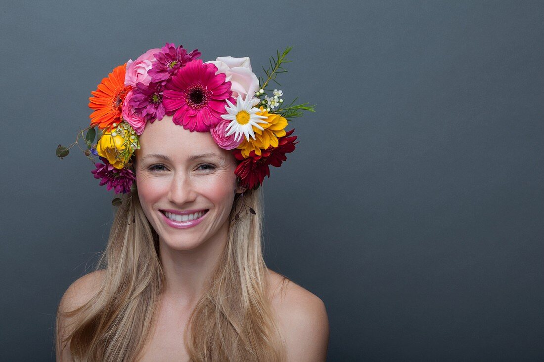 Junge blonde Frau mit buntem Blumenkranz auf dem Kopf