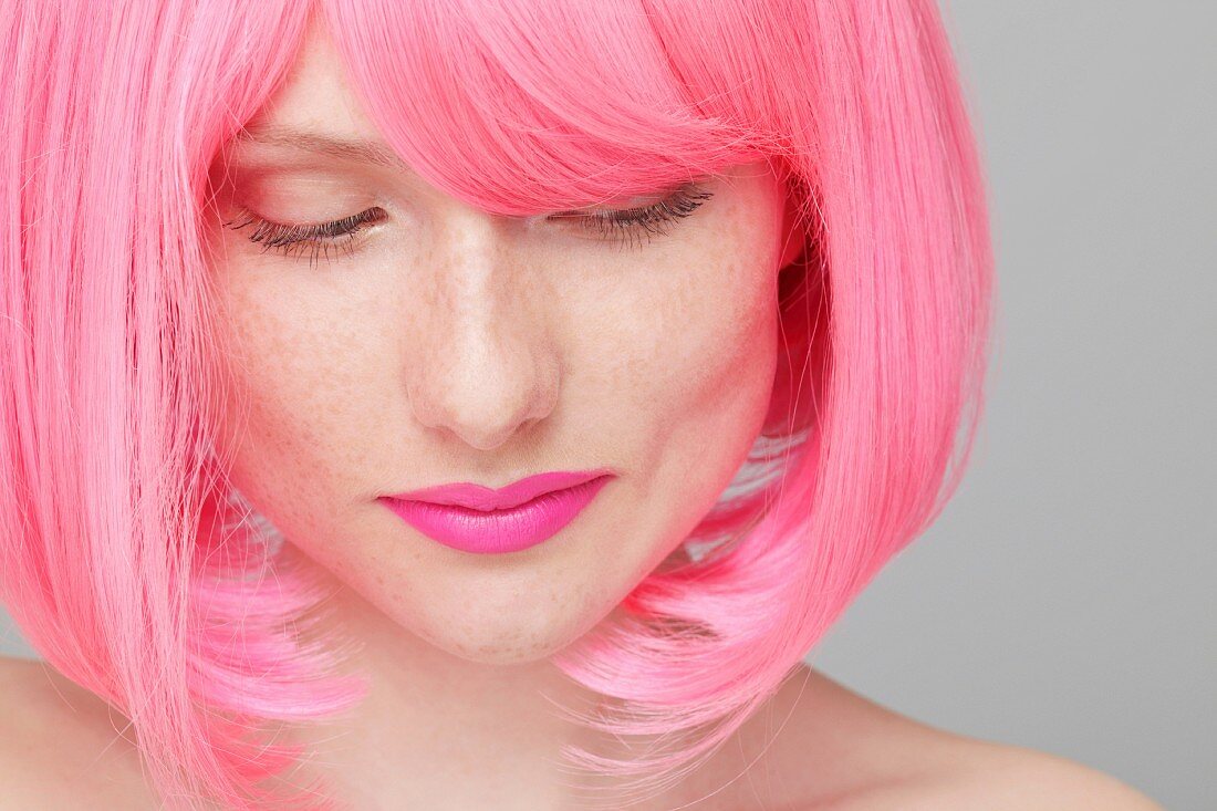 A young woman with a pink-coloured wig and lipstick