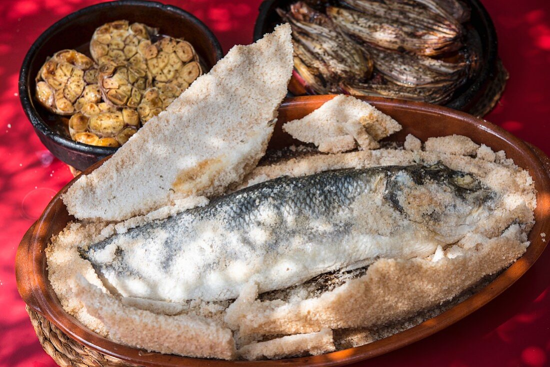 Sea bass in a salt crust with grilled garlic and onions