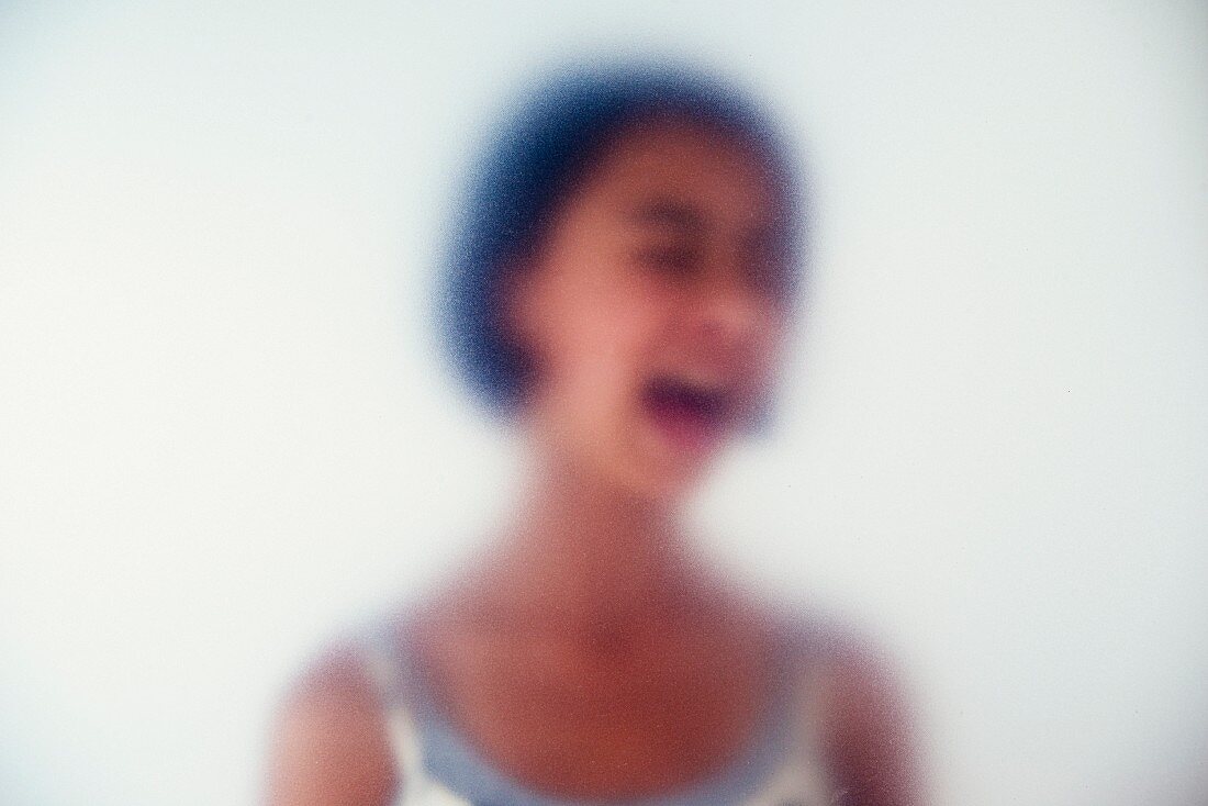 A young girl shouting behind frosted glass