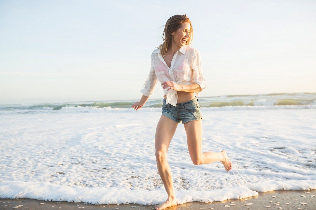 Junge Frau rennt am Strand entlang