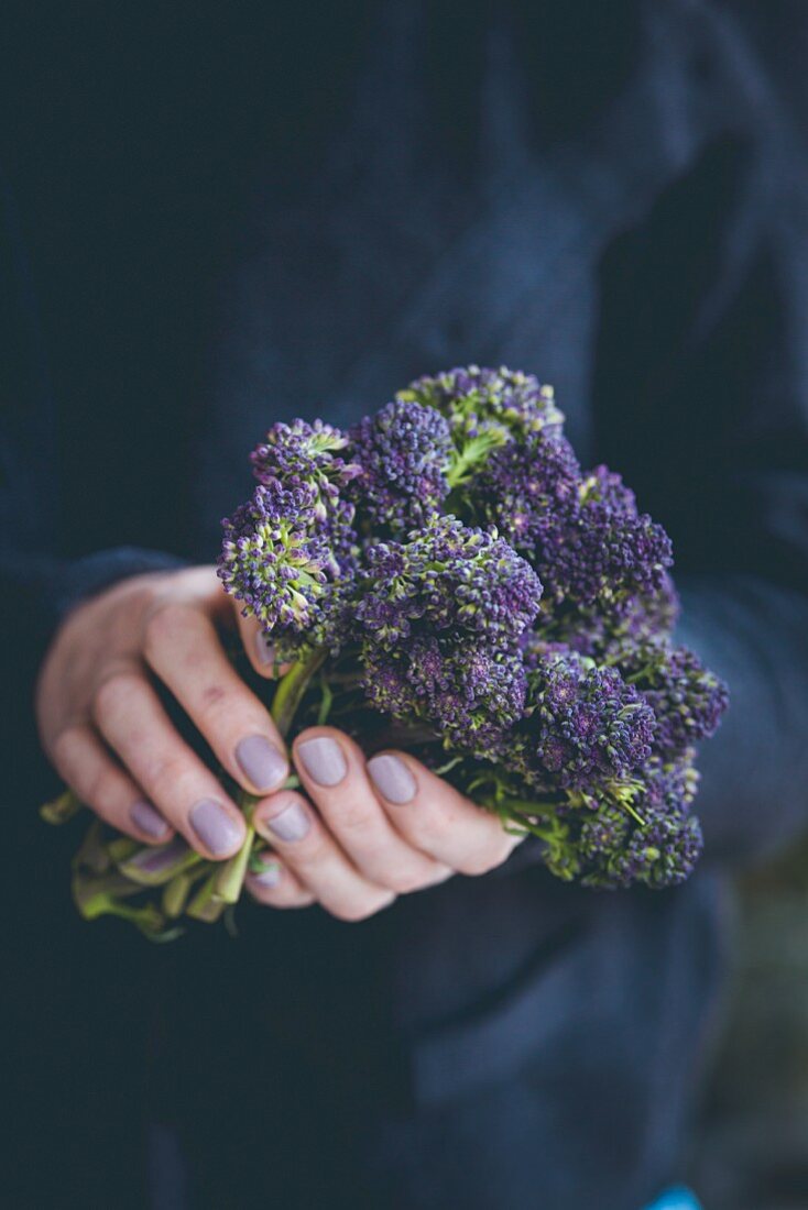 A woman holding purple tenderstem broccoli in her hands