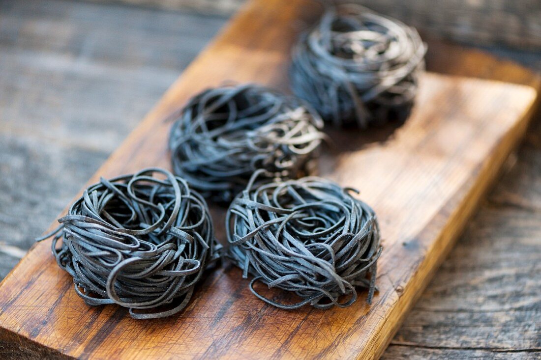 Pasta nests made of black sepia pasta on a wooden board