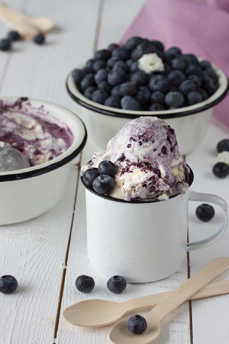 Blueberry ice cream in enamel cups and bowls