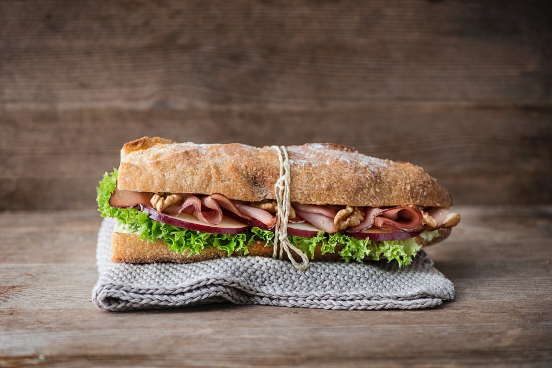 A baguette with Serrano ham, walnut, apple and frisee lettuce