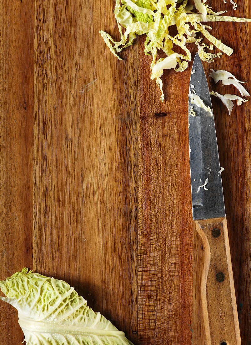 Choped savoy cabbage on a wooden surface with a knife
