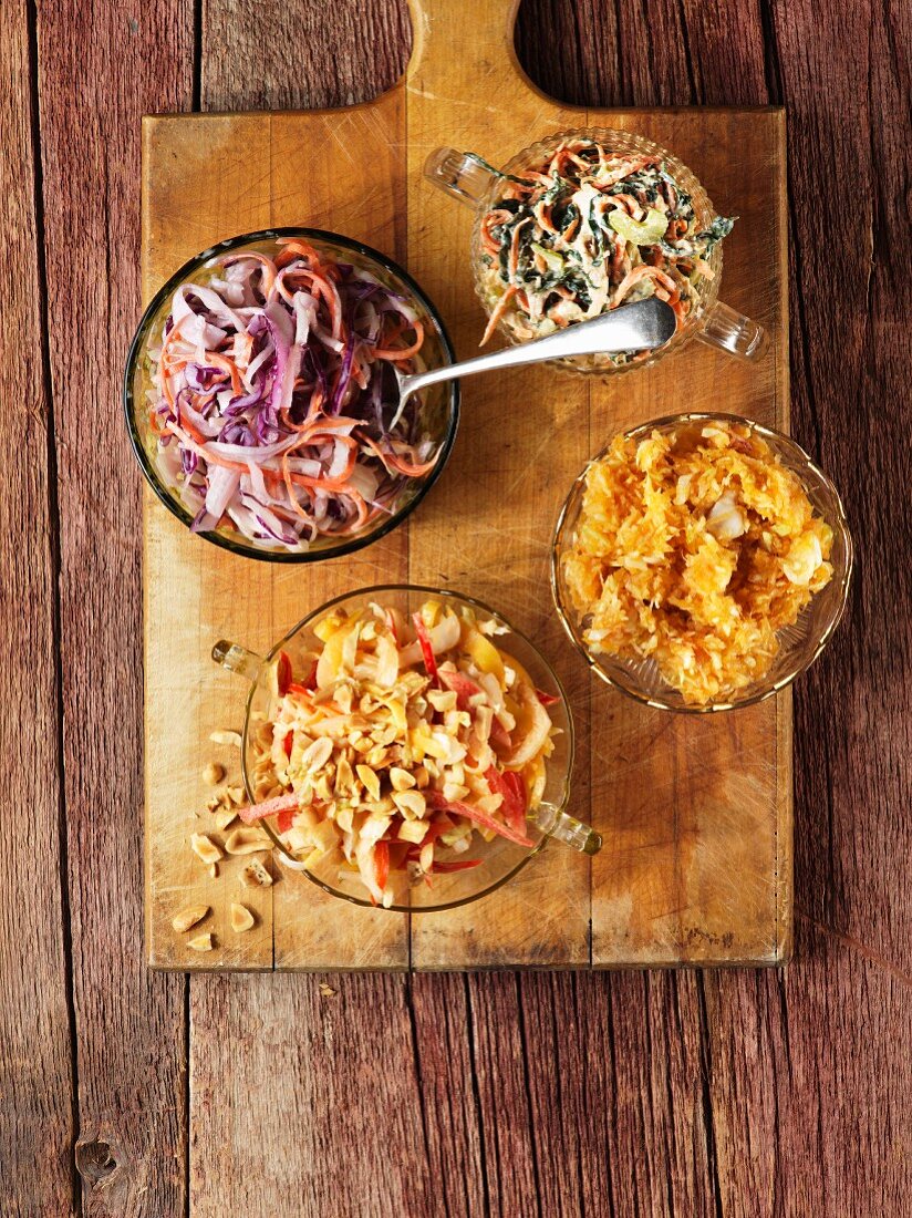 Assorted coleslaws on a wooden chopping board