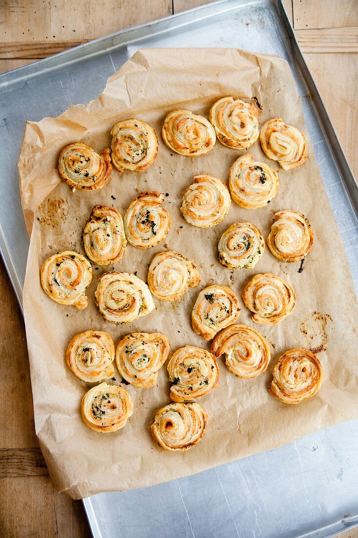 Freshly baked salmon puff pastry swirls on a baking sheet