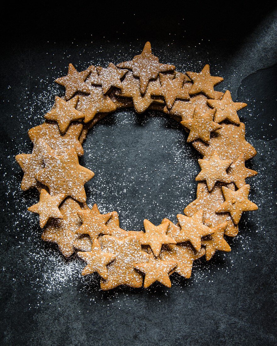 A wreath made of gingerbread stars dusted with icing sugar (seen from above)