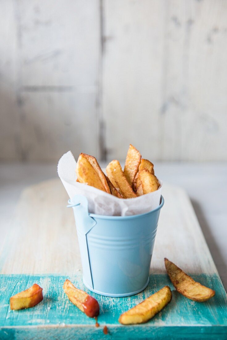 Chips in a small blue metal bucket with ketchup