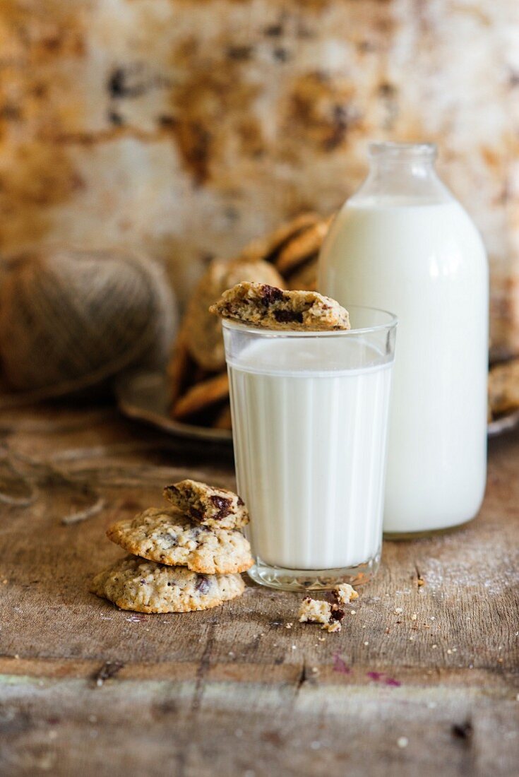 A glass and a bottle of milk and oat biscuits with chocolate chips