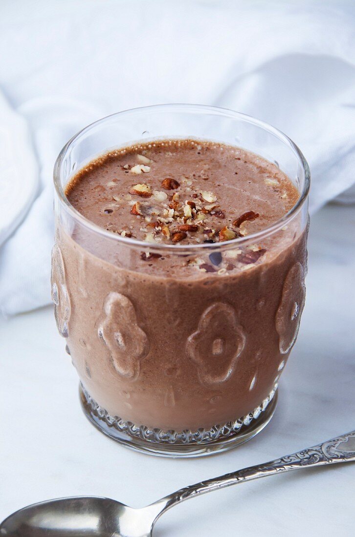 A high-protein chocolate & almond smoothie in a glass, topped with chopped nuts
