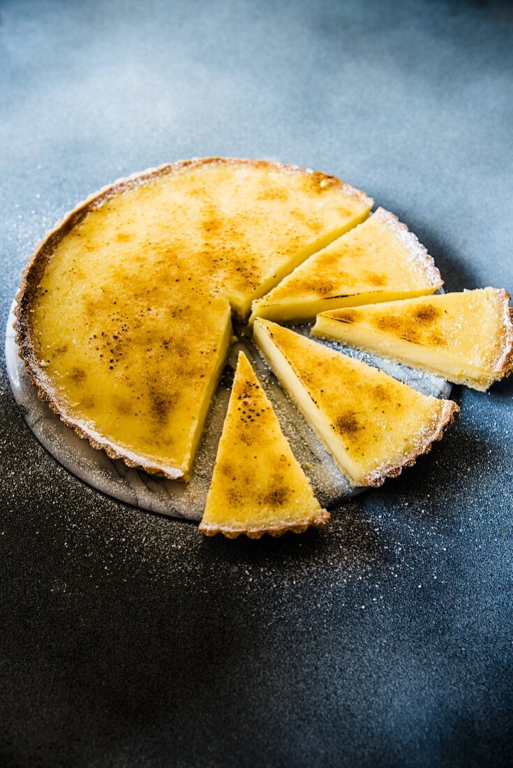 A sliced sugar-glazed lemon tart