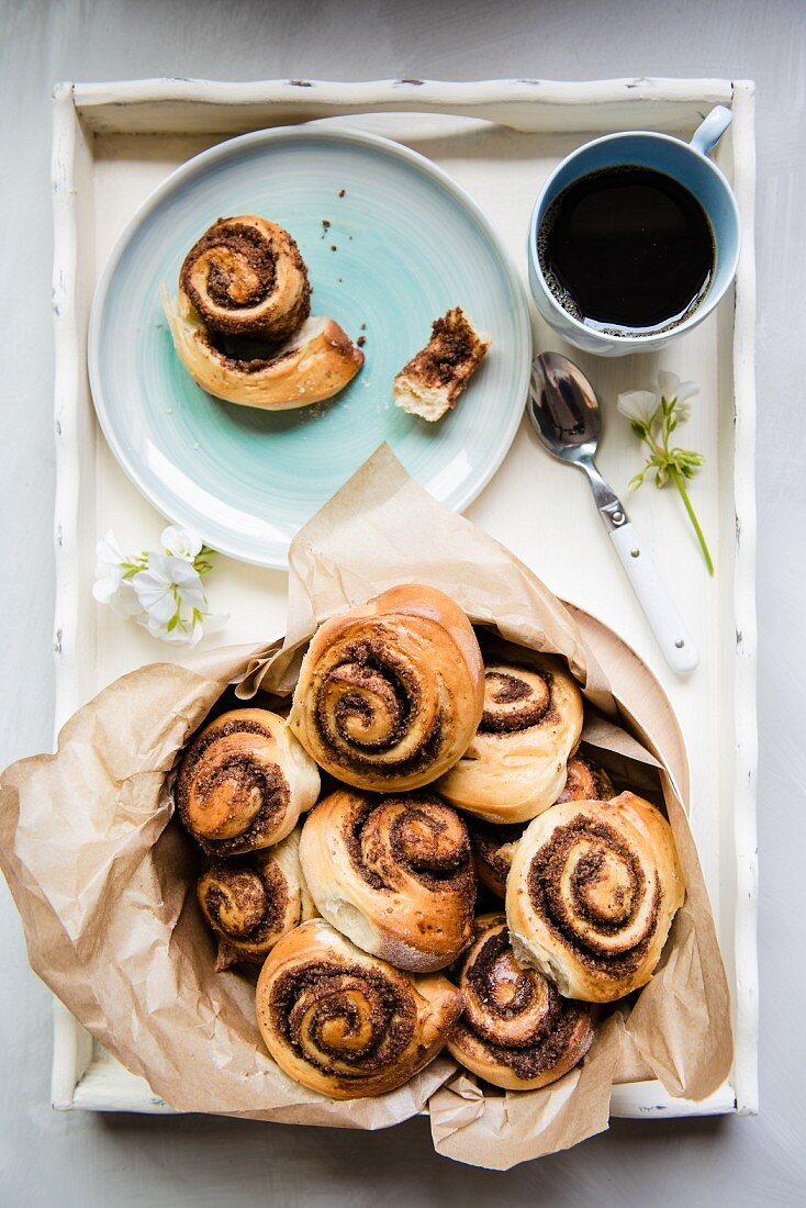 Sweet yeast swirls with a brown sugar, cinnamon and pecan nut filling on a tray with coffee