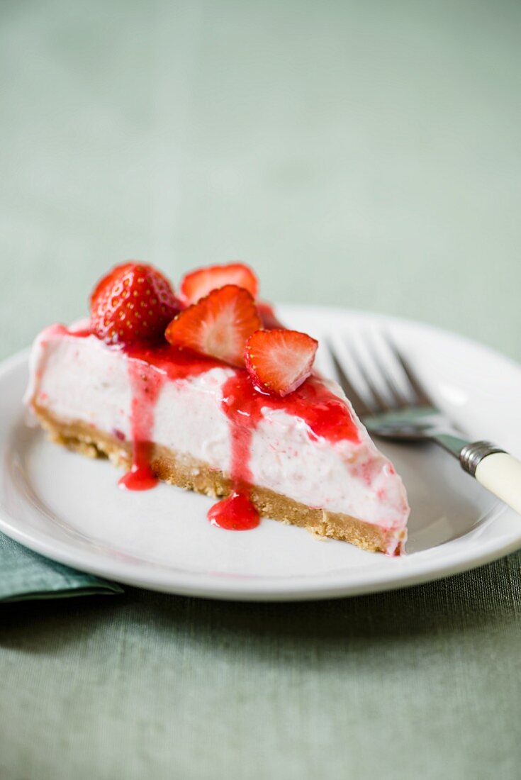 A slice of strawberry cheesecake on a plate with a fork