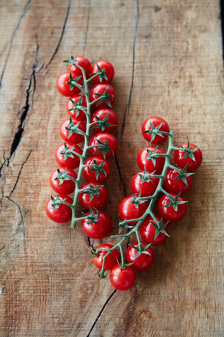 Cherry tomatoes on a vine on a wooden surface