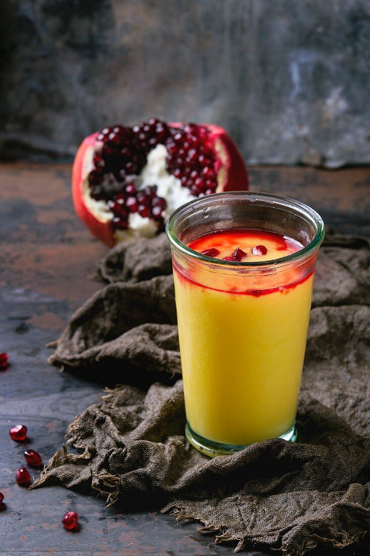 A glass of mango & pomegranate smoothie with pomegranate seeds