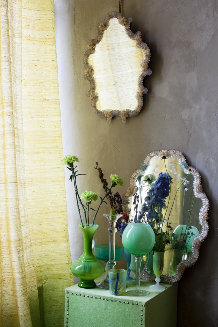 Arrangement mit Glasvasen, Blüten und Wandspiegel