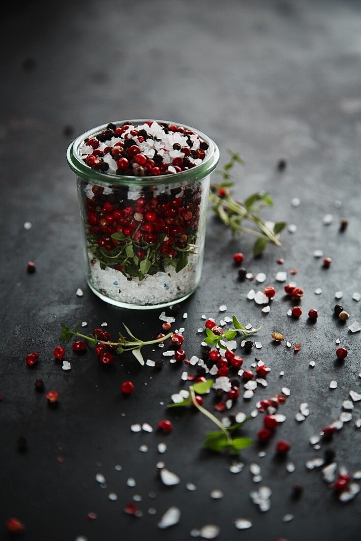 Sea salt, red pepper, black pepper and herbs in a glass