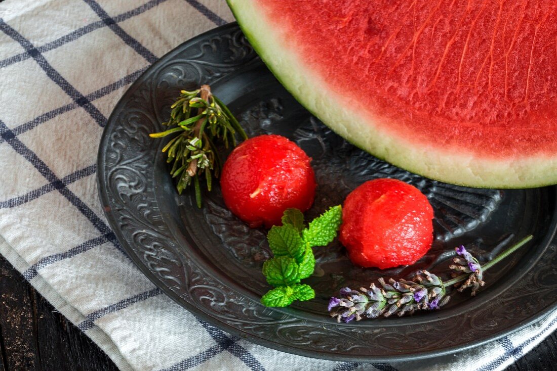 Wassermelone und Melonenkugeln mit Rosmarin und Minze auf Zinnteller