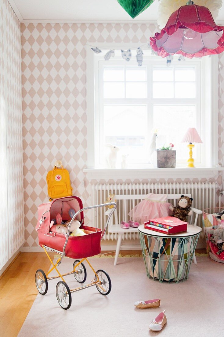Mädchenzimmer mit Rautenmuster-Tapete und rotem Retro Puppenwagen