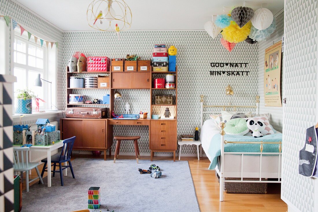 Patterned wallpaper, toys and retro cabinet in boy's bedroom with Scandinavian retro ambiance