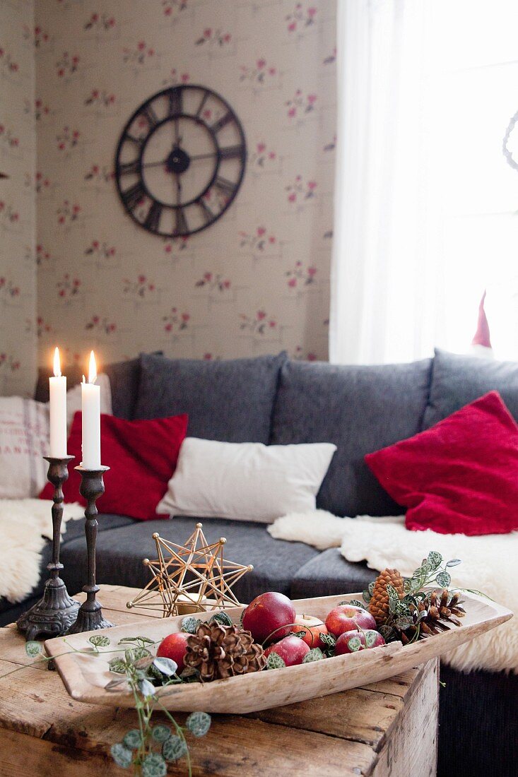 Weihnachtlich dekorierte Holzschale und brennende Kerzen auf rustikaler Holzkiste