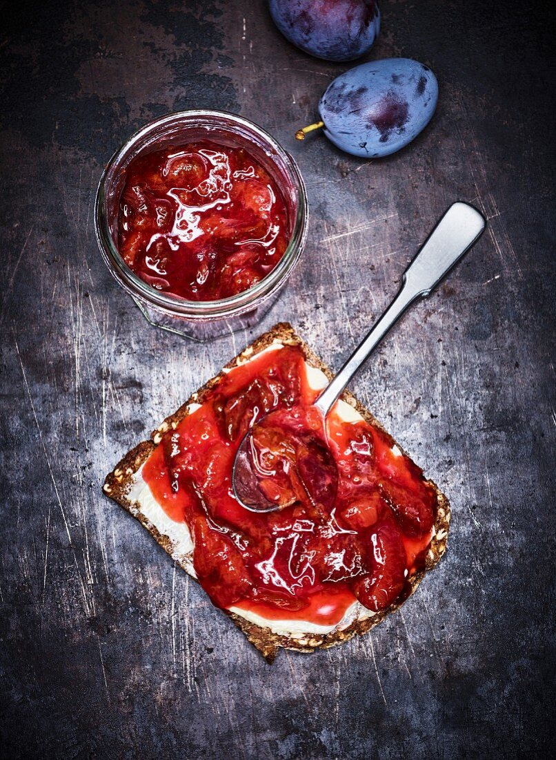 Home-made plum sauce in a glass jar and on bread