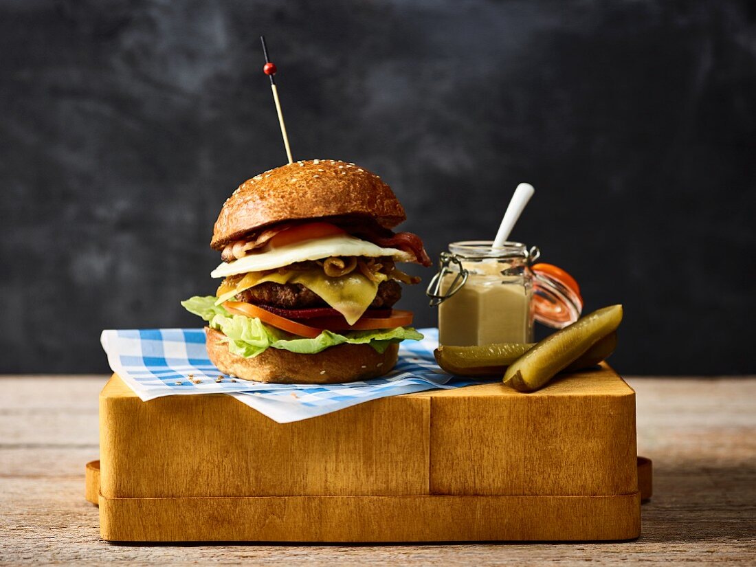A cheeseburger with mustard and gherkins