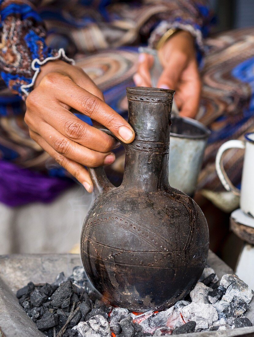 Frau bereitet Kaffee in Jebena (Kaffeekanne aus Ton) zu, traditionelle Kaffeezeremonie in Äthiopien